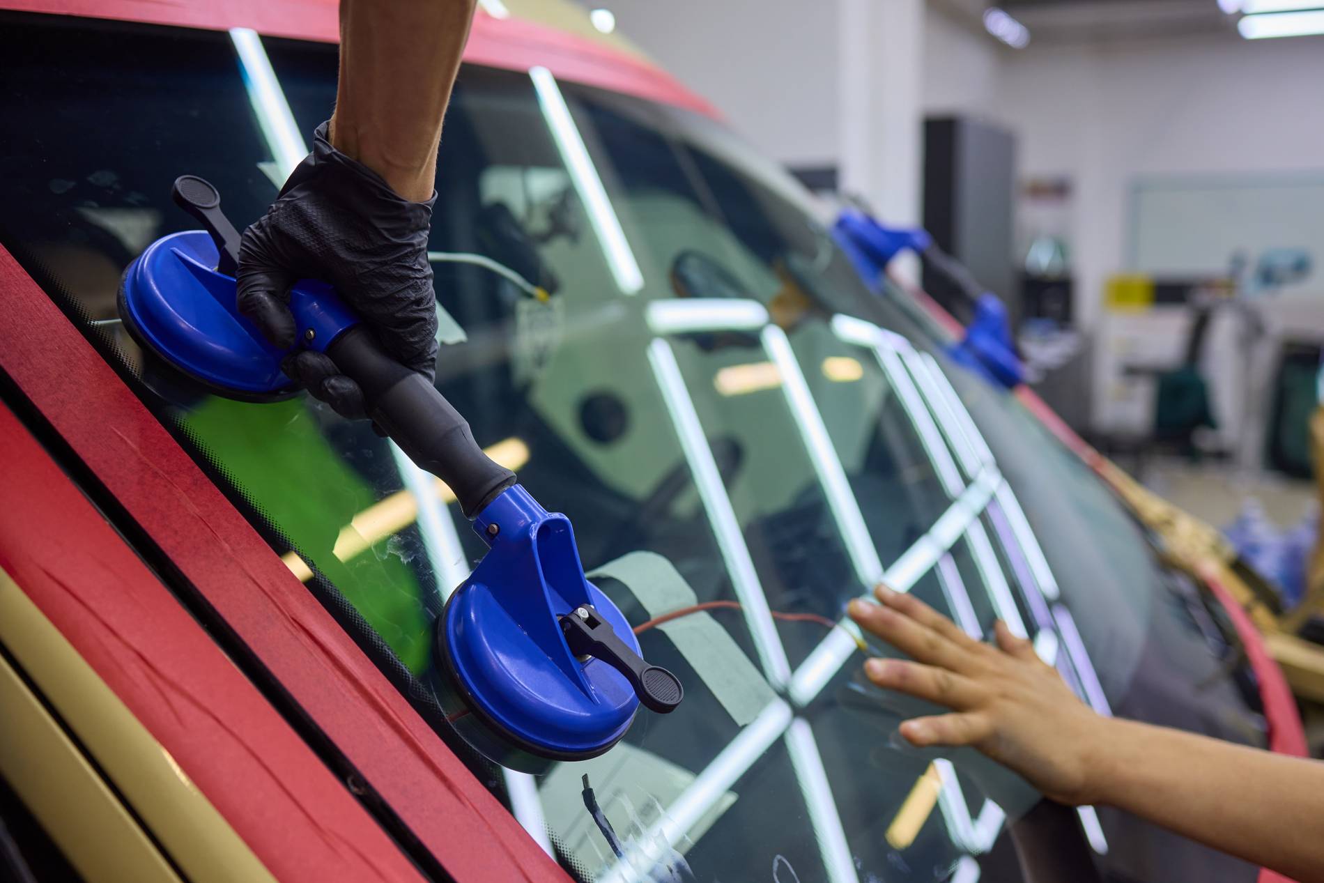 Installation d’un pare-brise automobile par un professionnel avec ventouses